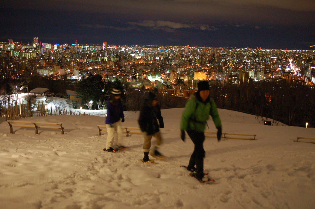Snowshoe trekking in night snow forest with hot wine / Sapporo